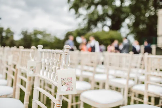 Rows of white chairs along a wedding ceremony aisle